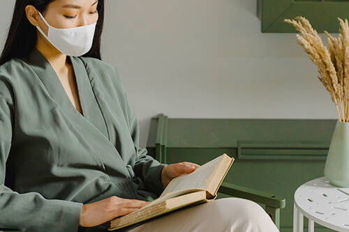 a woman reading while wearing a mask